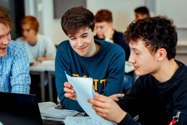 Tre smilende gutter ser på ark