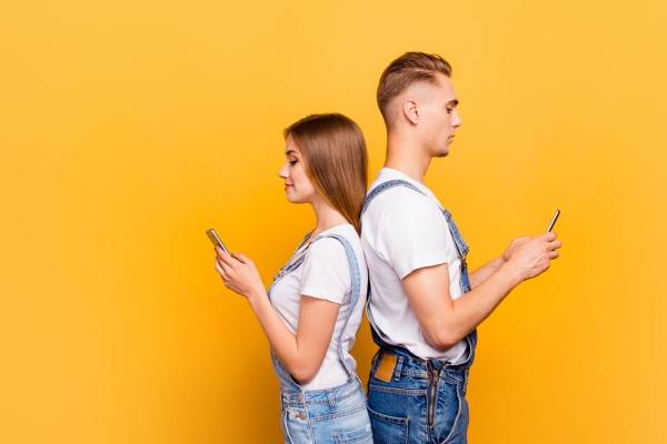 Jente og gutt holder hver sin mobil