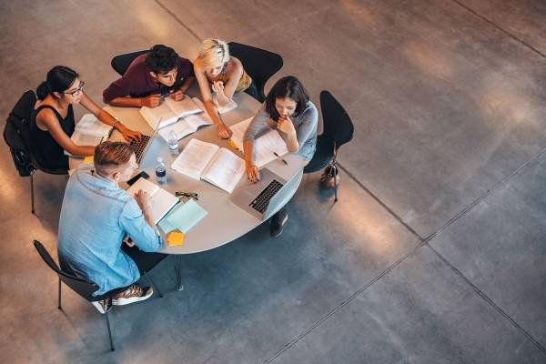 Elever sitter rundt et bord og leser sammen